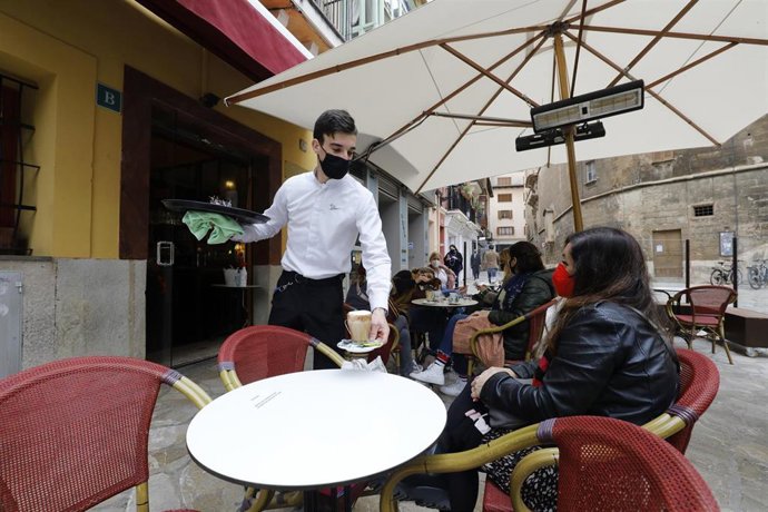 Archivo - Un camarero sirve un café en una terraza en Palma.