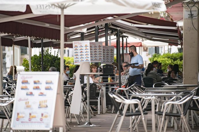 Un camarero atiende una mesa en la terraza de una cafetería