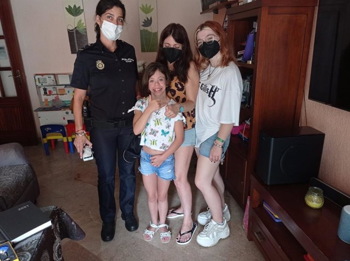 Un agente de la Policía Nacional de Huelva junto a la niña y su familia.