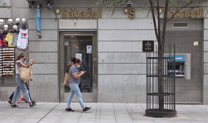 Varias personas pasan por una sucursal de Banco Sabadell, a 2 de septiembre de 2021, en Madrid (España).