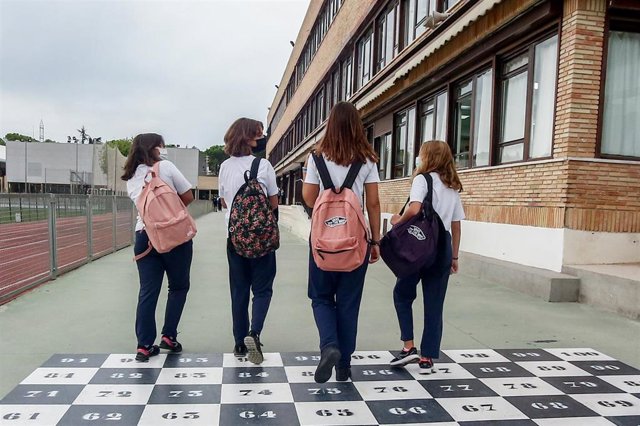 Cuatro niñas adolescentes se dirigen a la entrada de un colegio.