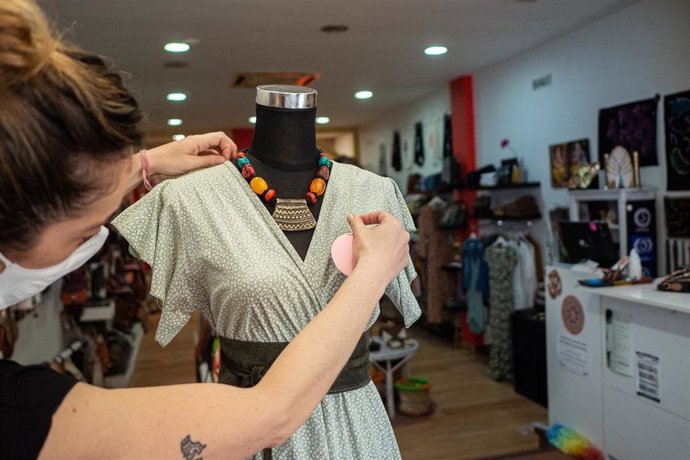 Archivo - Una trabajadora coloca ropa en un maniquí de su establecimiento, foto de recurso