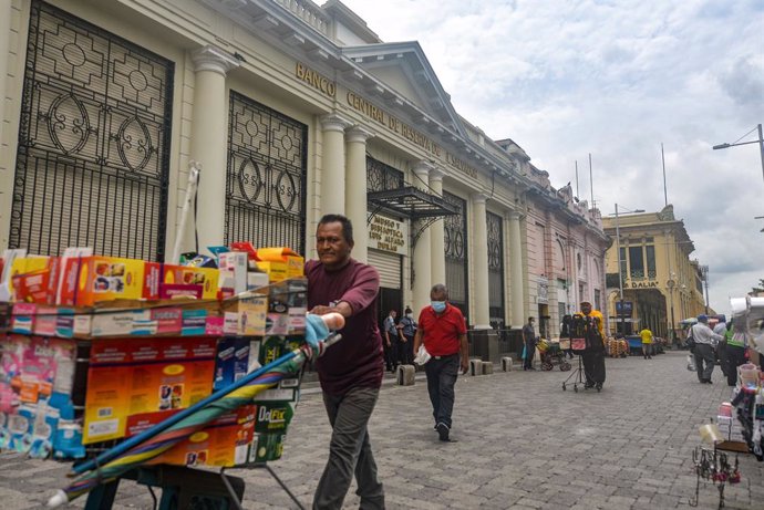Archivo - 09 June 2021, El Salvador, San Salvador: A man pushes a kart with various items for sale passes by a building of the Central Reserve Bank. El Salvador's Congress approved the digital currency Bitcoin as a legal tender, meanwhile, Salvadoran Pr