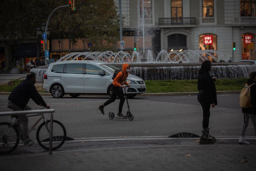 Archivo - Un hombre en bici y un joven en patinete en Barcelona