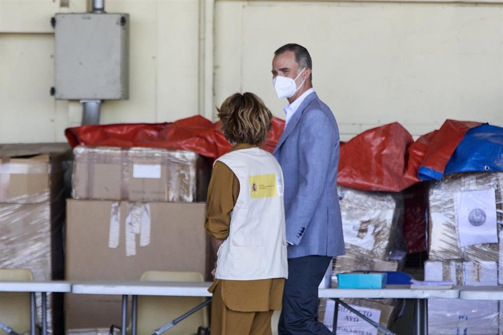 El Rey Felipe VI conversa con una cooperante a su llegada al hangar para visitar el dispositivo provisional en Torrejón de Ardoz