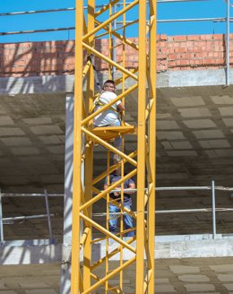 Imagen del empresario subcontratista de las viviendas de Cisneo Alto encaramado a una grúa de la obra ante un mediador de la Policía Nacional