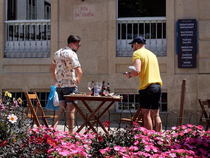 Dos hombres abandonan una terraza de un restaurante de la Rua da Raiña, a 12 de agosto de 2021, en Santiago de Compostela