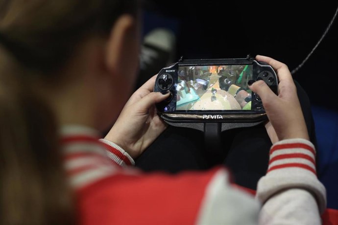 Archivo - Niña juega con dispositivo móvil