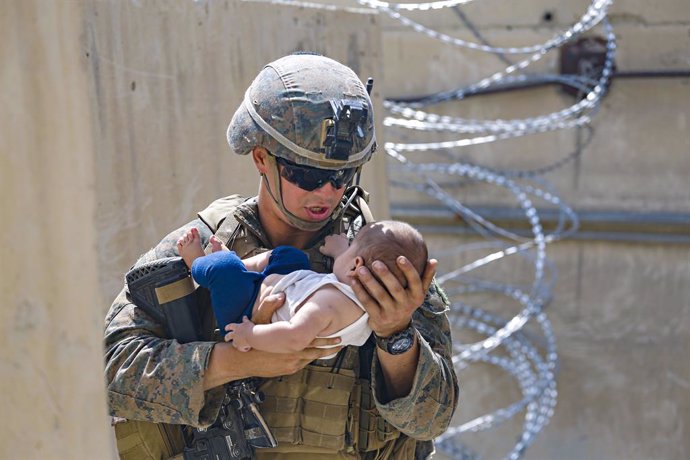 HANDOUT - 21 August 2021, Afghanistan, Kabul: A US marine soldier carries a young boy at the Hamid Karzai International Airport during the evacuation of civilians following the Taliban takeover. Photo: Lcpl. Nicholas Guevara/U.S. Mari/Planet Pix via ZUM
