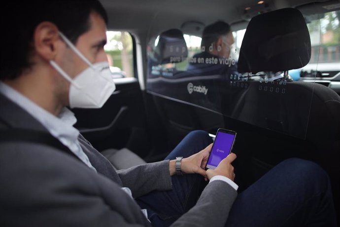 Archivo - Un cliente protegido con mascarilla viaja en un coche conducido por un trabajador protegido con mascarilla .