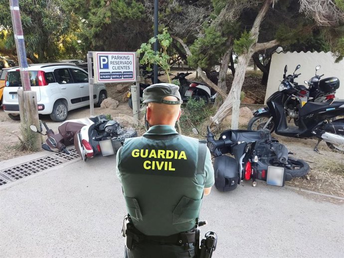 Un agente de la Guardia Civil junto a motos tiradas en Formentera.