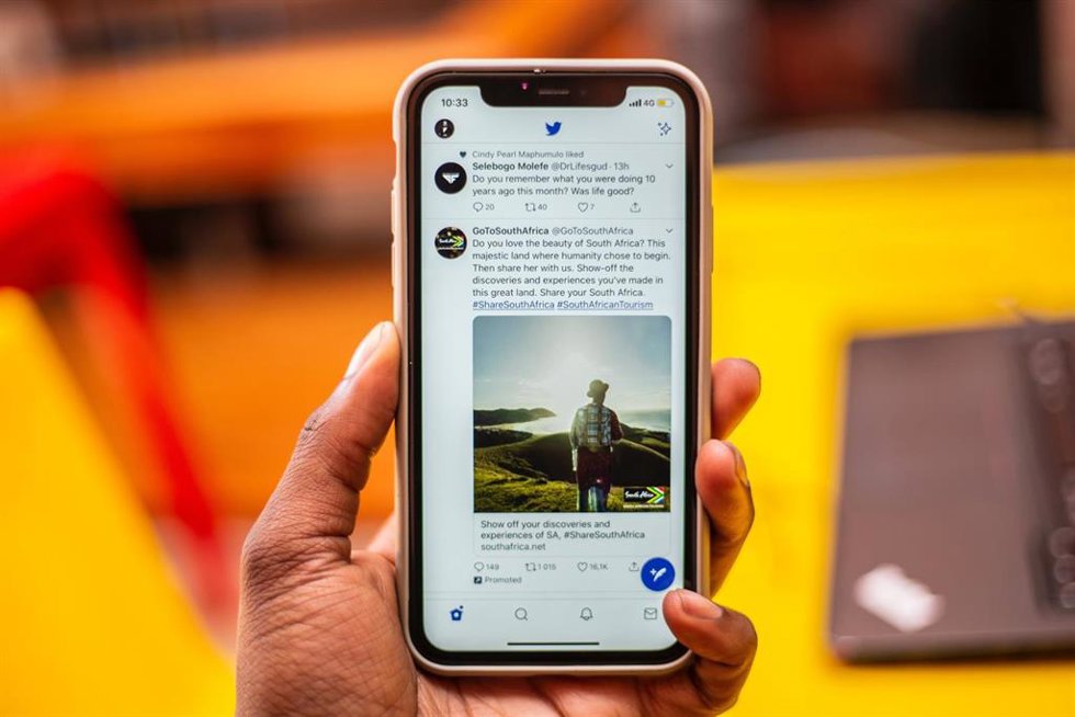 Archivo - Hombre sujetando un iPhone con la interfaz de Twitter