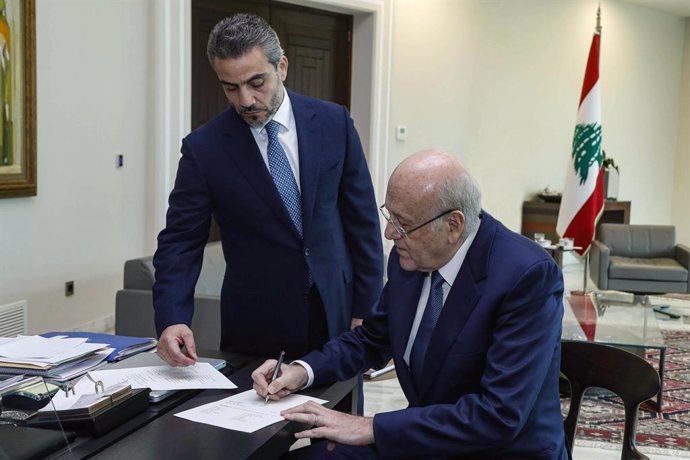 HANDOUT - 10 September 2021, Lebanon, Baabda: Lebanese Prime Minister Najib Mikati (R) signs a decree to form a long-awaited government comprising 24 ministers in an effort to tackle the country's worst economic crisis since the 1975-1990 civil war ende