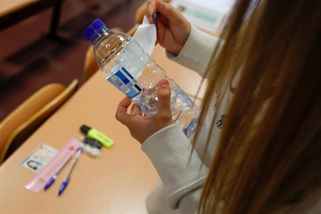Archivo - Una joven despega el papel de la botella cumpliendo las normas a seguir para la convocatoria extraordinaria de la Evaluación del Bachillerato para el Acceso a la Universidad (EBAU), a 6 de julio de 2021, en Madrid, (España). Un total de 6.213 