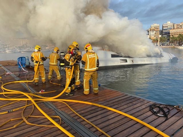 Bomberos de Palma trabajando en el incendio de un catamarán en el puerto de Palma.