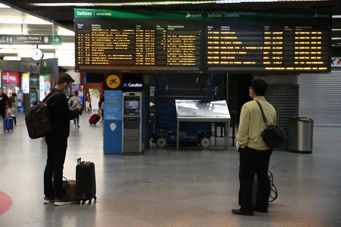 Archivo - Dos hombres observan un panel informativo en la estación de Madrid - Puerta de Atocha, a 14 de mayo de 2021, en Madrid (España). Este viernes comienza el primer fin de semana completo sin el estado de alarma. 