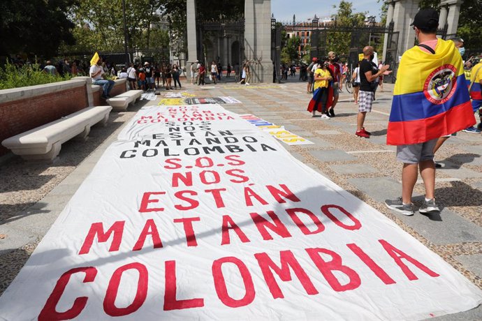 Una pancarta donde se lee "Nos están matando", en una manifestación contra la llegada del presidente de Colombia a Madrid, en la Puerta de Alcalá, a 12 de septiembre de 2021, en Madrid (España). Esta manifestación protesta contra la llegada del mandatar