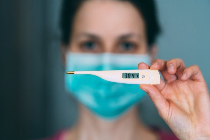 Archivo - Imagen de recurso de una mujer con un termómetro y mascarilla.