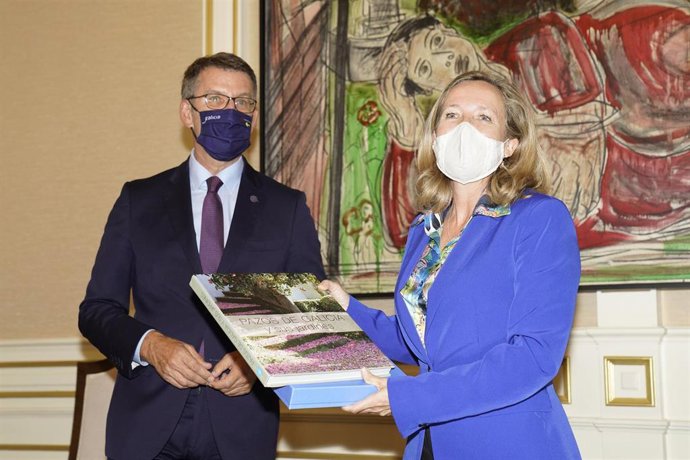 El presidente de Galicia, Alberto Núñez Feijoo, regala un libro de los Pazos y jardines de Galicia a la vicepresidenta primera del Gobierno y ministra de Asuntos Económicos y Transformación Digital, Nadia Calviño, a su llegada a la rueda de prensa, desp
