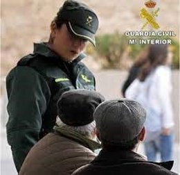 Una agente de la Guardia Civil conversa con dos hombres.