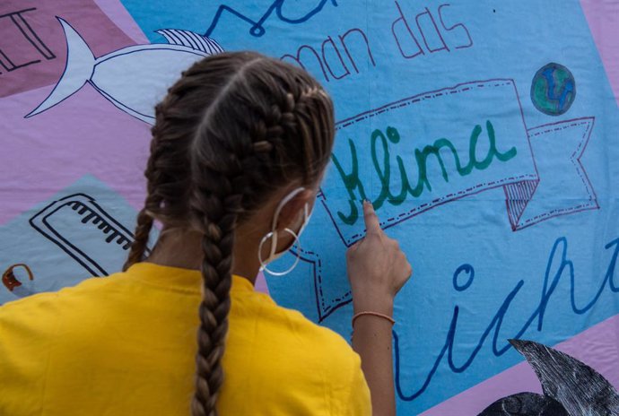 Archivo - 30 July 2021, Berlin: A young environmental activist puts up an election poster in front of the German Reichstag building to mark the start of the "vote4me" children's campaign called by the environmental protectIon organisation Greenpeace. Ph