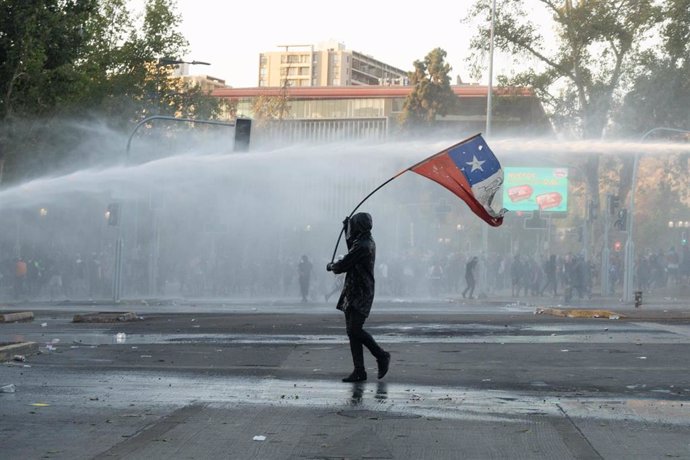 Archivo - Imagen de archivo de una persona sosteniendo una bandera de Chile durante unas manifestaciones en Santiago, la capital.