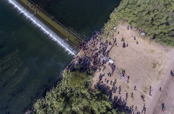16 September 2021, US, Del Rio: Migrants pass back-and-forth on a weir dam on the Rio Grande nearby the international bridge connecting Del Rio, Texas and Ciudad Acuna, Mexico as they wait to be processed by immigration officials. Photo: William Luther/