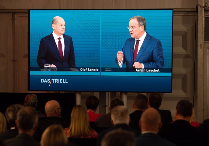 12 September 2021, Berlin: People look at a screen during a TV discussion for chancellor candidates on ARD and ZDF between (R-L) Armin Laschet, Minister President of North Rhine-Westphalia and candidate for chancellor of the Christian Democratic Union (