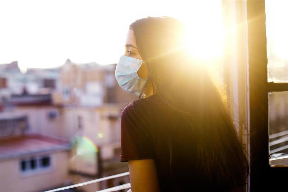 Archivo - Una joven asomándose a la ventana de su vivienda