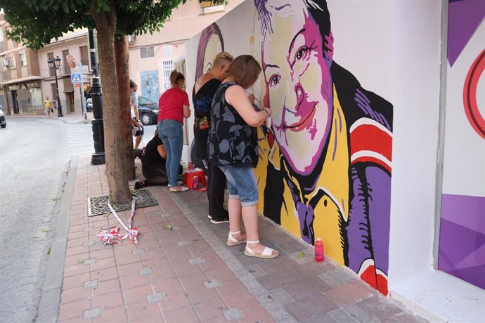 Mujeres participan en la pintura del muro