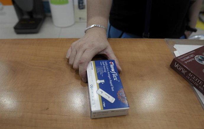 Archivo - Un cliente enseña un test de antígenos de detección del COVID-19 en una farmacia.
