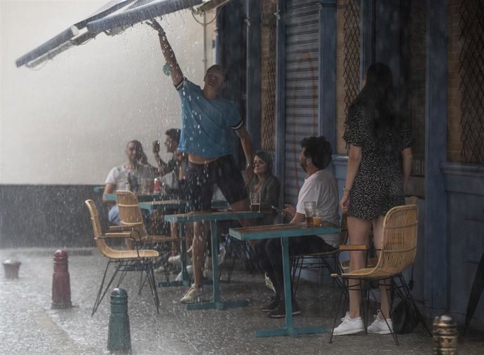 Varias personas en la terraza de un bar durante una tormenta. A 14 de septiembre de 2021, en Sevilla (Andalucía, España).