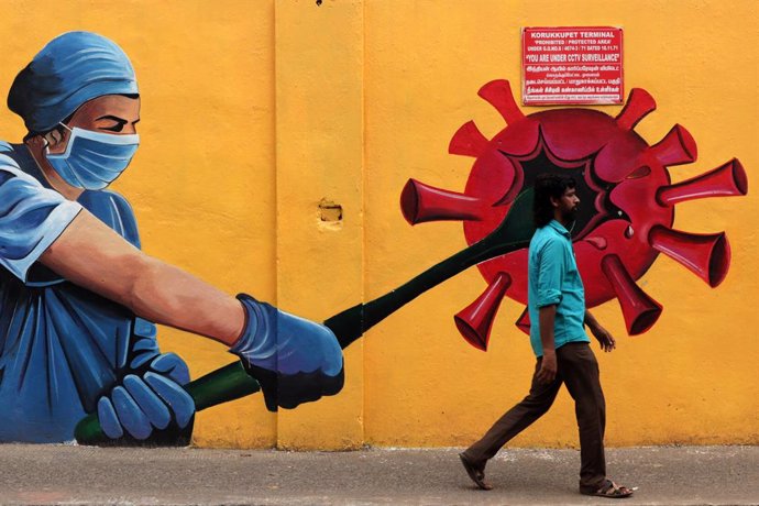 Un hombre pasea junto a un mural sobe la pandemia de coronavirus en India