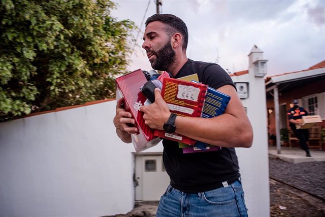 Un hombre sale de su casa con libros durante la evacuación en La Palma