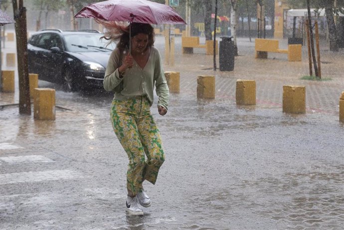 Una  mujer cruza un charco durante una tormenta.