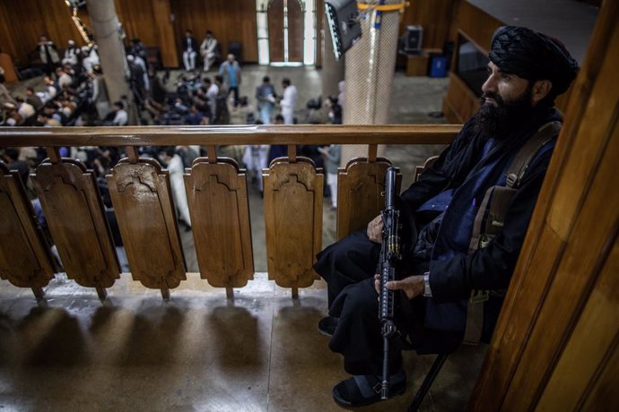 21 September 2021, Afghanistan, Kabul: A Taliban fighter sits guard as Taliban government spokesman Zabihullah Mujahid delivers a news conference in Kabul. Further ministers and deputies were named as part of the Taliban interim government, none of them