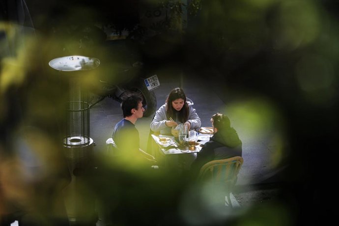 Archivo - Tres personas en la terraza de un bar.