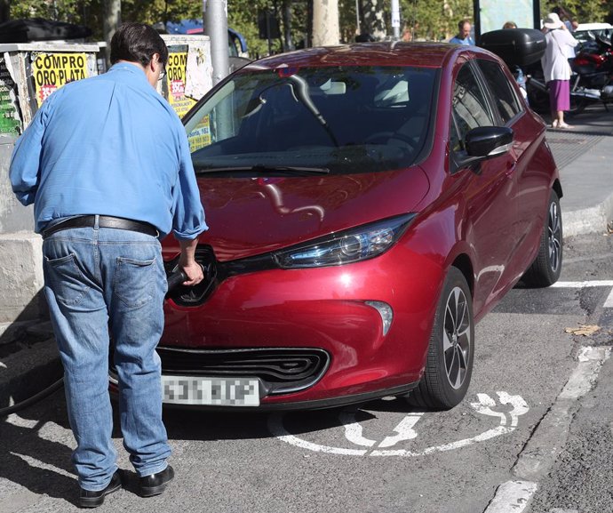 Archivo - Un hombre carga su coche en un punto de carga para coches eléctricos en Madrid.