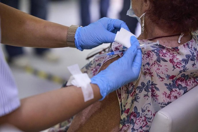 Una sanitaria vacuna a una mujer.