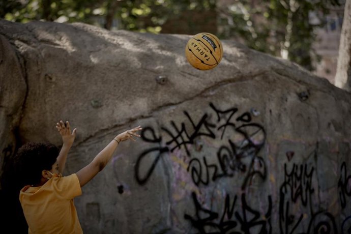 Archivo - Un niño juga al baloncesto