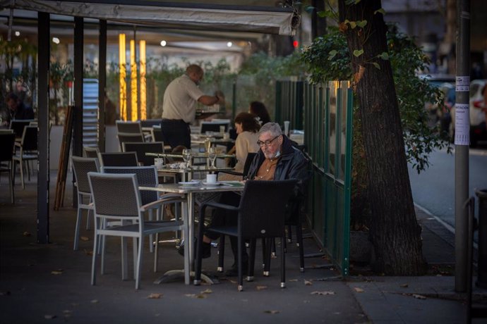 Archivo - Un hombre lee en una terraza durante el primer día del inicio del primer tramo de la desescalada de la segunda ola por el coronavirus en Barcelona, Catalunya (España), a 23 de noviembre de 2020