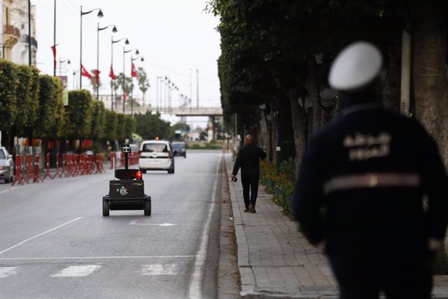 Archivo - Un policía en Túnez junto a un robot encargado de comprobar si se cumple el confinamiento por coronavirus