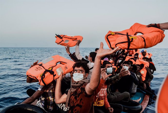 Archivo - HANDOUT - 04 July 2021, Italy, ---: Migrants in a small boat take life jackets from the helpers as they sit in a small boat in the Mediterranean Sea. The Ocean Viking rescue vessel has pulled 67 people from the central Mediterranean Sea, SOS M