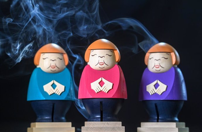 22 September 2021, Saxony, Seiffen: A picture made available on 24 September 2021 shows three incense burner figurines of German Chancellor Angela Merkel doing her trademark hand gesture at the Seiffener Volkskunst workshop. The Merkel-themed burners ha