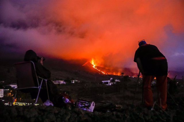 Vecinos y turistas observan el cono del volcán de Cumbre Vieja tras la explosión de su crater producida este sábado