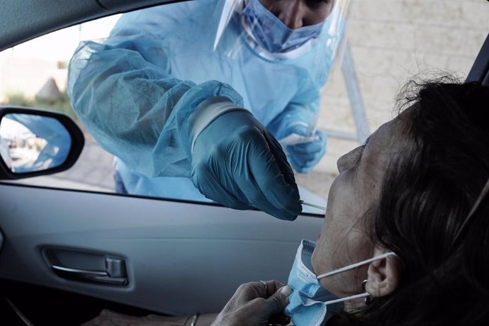 17 September 2021, Israel, Lod: A health worker takes a swab from a woman for a coronavirus PCR test at a drive-thru facility at Ben Gurion International Airport in line with the Israeli government's decision requiring all departing passengers to presen