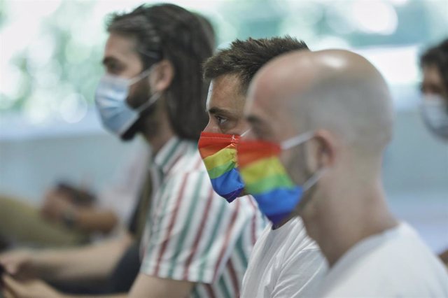 Archivo - Dos hombres se protegen con mascarillas con la bandera LGTB 