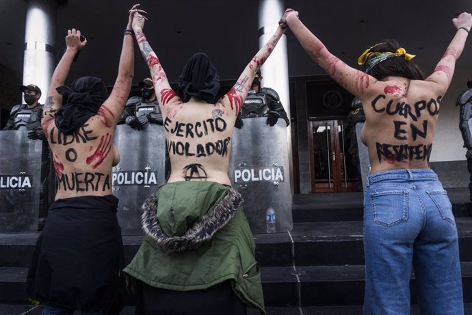 Archivo - 29 June 2020, Colombia, Bogota: Slogans against the army are seen on the backs of demonstrators during a demonstration outside the main military unit of Bogota against a reported rape of a young Embera Chami indigenous girl by 7 soldiers. Phot