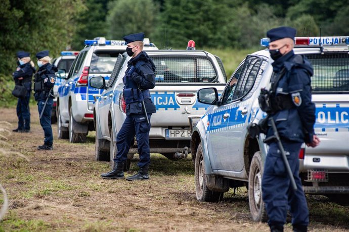 01 September 2021, Poland, Usnarz Gorny: Police officers stand on guard next to the village of Usnarz Gorny near a makeshift camp where a group of migrants stay and are not being let into the Polish side. The Polish government is introducing a State of 