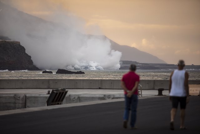 Dos personas observan la columna de humo y la lava del volcán de Cumbre Vieja a su llegada al Océano Atlántico, a 29 de septiembre de 2021, en La Palma, Santa Cruz de Tenerife, Islas Canarias, (España).